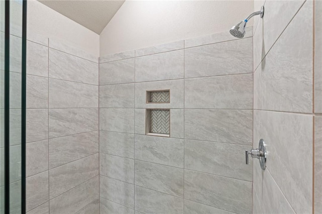 bathroom with tiled shower and vaulted ceiling