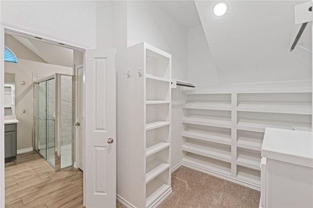 walk in closet with lofted ceiling and light hardwood / wood-style floors