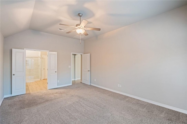 unfurnished bedroom with ceiling fan, ensuite bathroom, vaulted ceiling, and light carpet