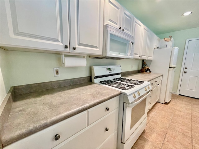 kitchen with white appliances, white cabinetry, and light tile patterned floors