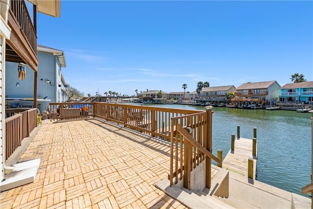 view of patio with a residential view, a water view, and a dock