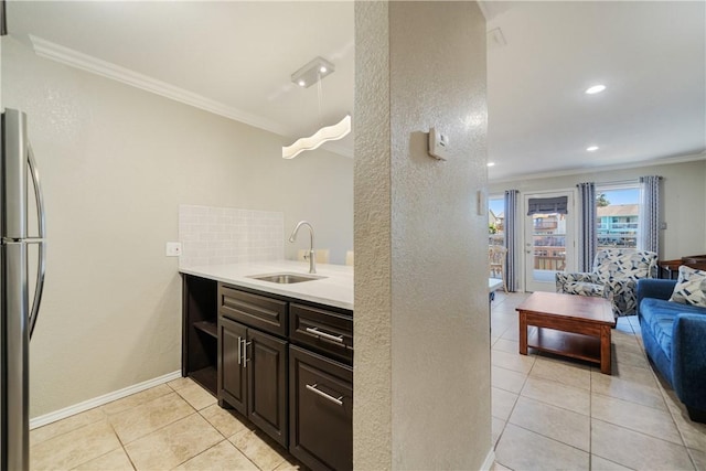 kitchen with backsplash, crown molding, open floor plan, freestanding refrigerator, and a sink