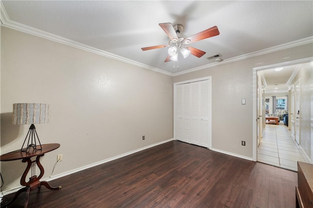 bedroom with visible vents, wood finished floors, a closet, crown molding, and baseboards