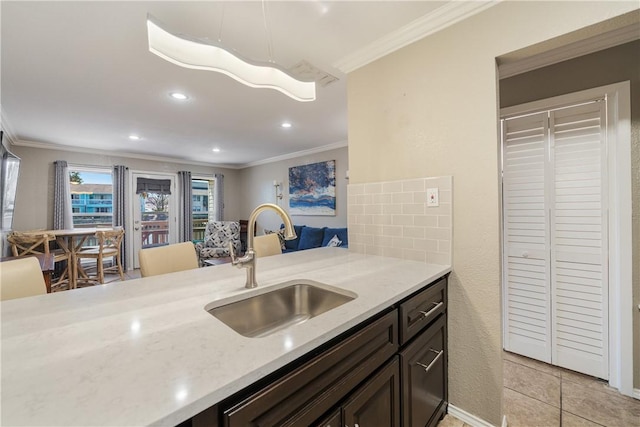 kitchen featuring crown molding, dark brown cabinets, and a sink