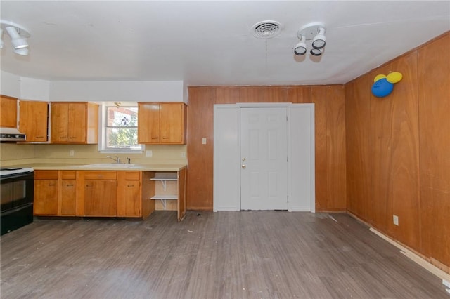 kitchen featuring wooden walls, exhaust hood, sink, dark hardwood / wood-style floors, and black electric range oven