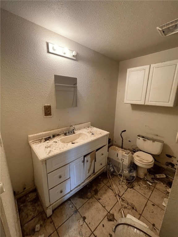 bathroom featuring tile patterned flooring, vanity, a textured ceiling, and toilet