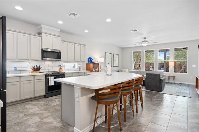 1962 Lighthouse Lakes Ln, Aransas Pass, TX 78336 - kitchen with a ceiling fan, light countertops, electric range, stainless steel microwave, and visible vents