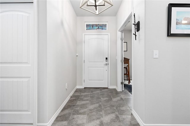 1962 Lighthouse Lakes Ln, Aransas Pass, TX 78336 - doorway to outside featuring stone finish floor, baseboards, and an inviting chandelier