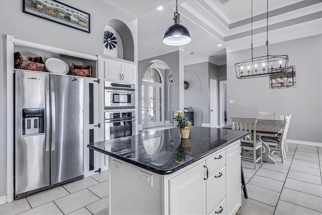 kitchen featuring dark stone countertops, appliances with stainless steel finishes, a kitchen island, white cabinetry, and decorative light fixtures