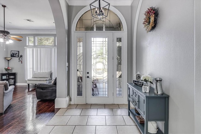 foyer featuring ceiling fan with notable chandelier, ornamental molding, and light wood-type flooring