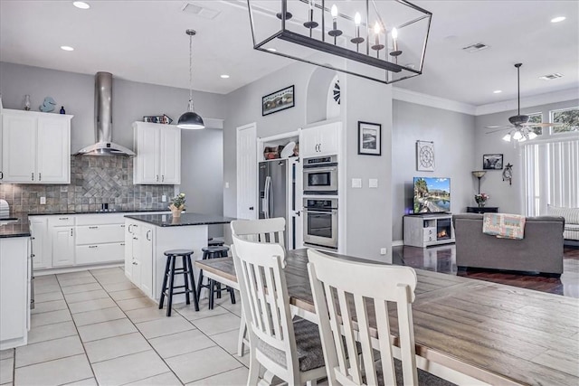 kitchen featuring white cabinets, wall chimney range hood, tasteful backsplash, and a center island