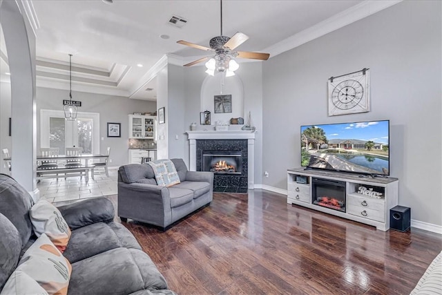 living room featuring dark wood-type flooring, ceiling fan, and ornamental molding