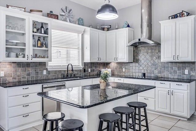 kitchen with decorative light fixtures, white cabinets, wall chimney range hood, and dishwasher