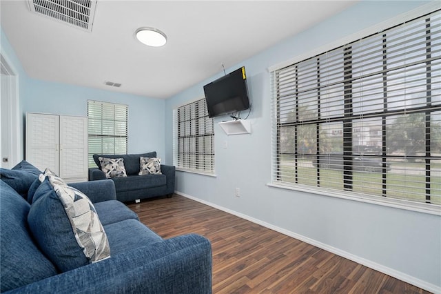 living area featuring baseboards, visible vents, and dark wood-type flooring