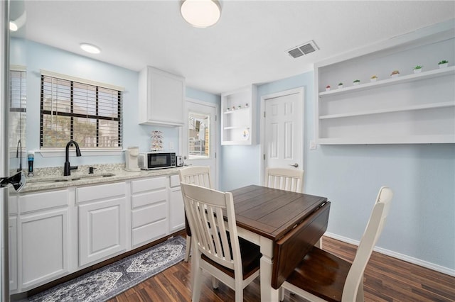 kitchen featuring light stone countertops, white cabinets, visible vents, and open shelves