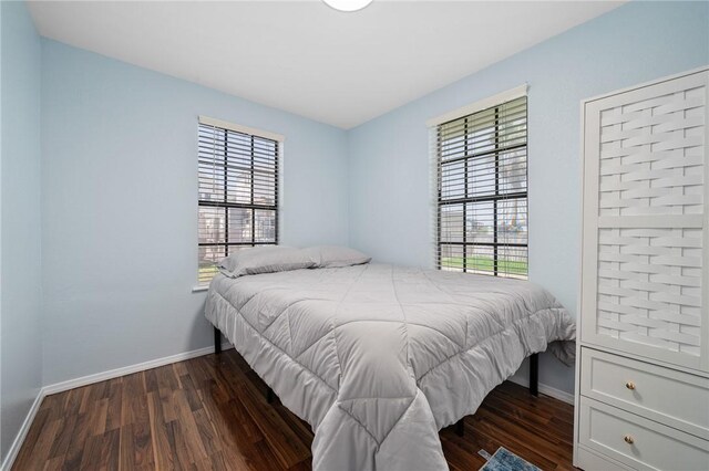 bedroom with dark wood-type flooring and baseboards