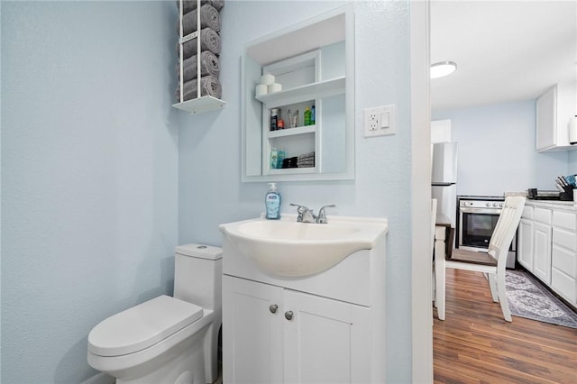 bathroom with toilet, wood finished floors, and vanity