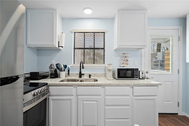 kitchen featuring appliances with stainless steel finishes, white cabinetry, a sink, and dark wood-style floors