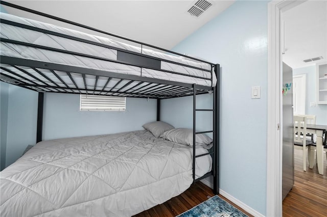 bedroom with baseboards, visible vents, and wood finished floors