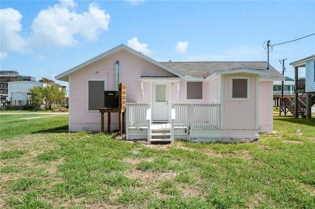 rear view of house with a yard and roof with shingles