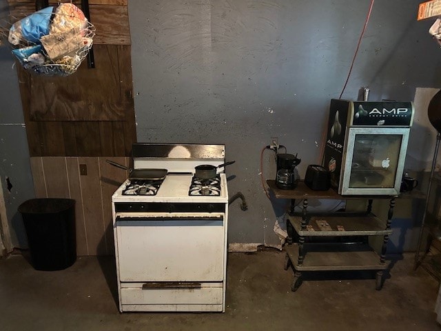 kitchen featuring white range with gas cooktop and concrete floors