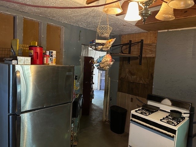 kitchen with concrete flooring, wood walls, white gas stove, and stainless steel refrigerator