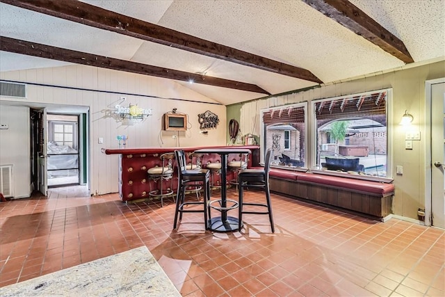 434 Cape Lookout Dr, Corpus Christi, TX 78412 - tiled dining space with visible vents, a dry bar, lofted ceiling with beams, and a textured ceiling