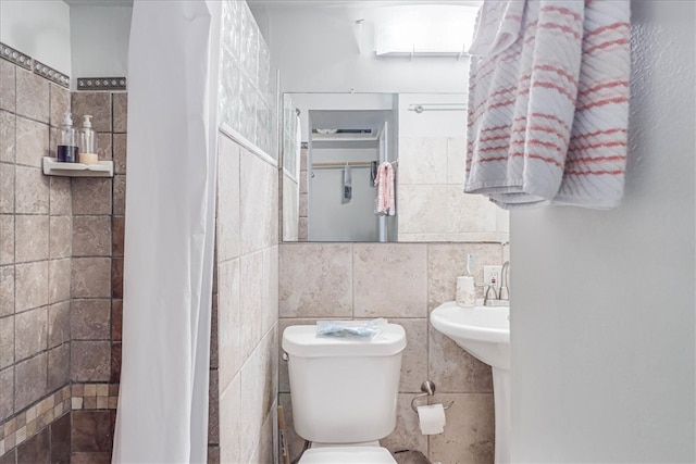 bathroom with walk in shower, toilet, and tile walls