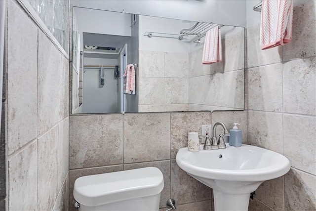 bathroom featuring toilet and tile walls