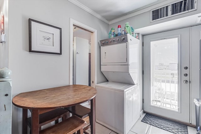 laundry area with crown molding, light tile patterned flooring, and stacked washer / drying machine