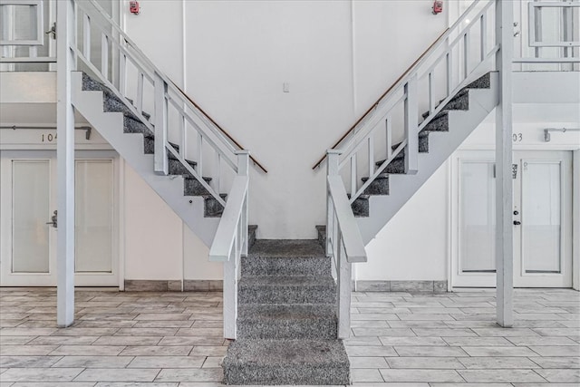 staircase featuring hardwood / wood-style floors, a towering ceiling, and french doors