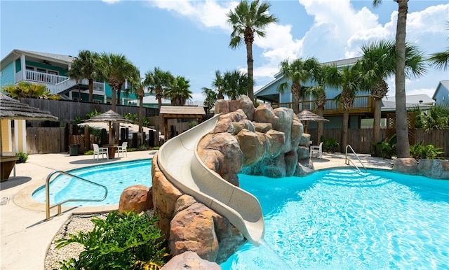 view of pool with a water slide and a patio area