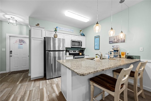 kitchen featuring appliances with stainless steel finishes, pendant lighting, sink, white cabinets, and kitchen peninsula