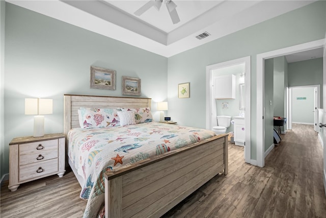 bedroom with dark wood-type flooring, ceiling fan, and ensuite bath