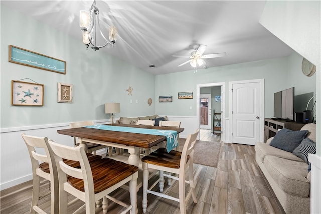 dining space with light wood-type flooring and ceiling fan with notable chandelier