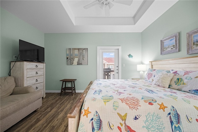 bedroom featuring dark wood-type flooring, a raised ceiling, ceiling fan, and access to exterior