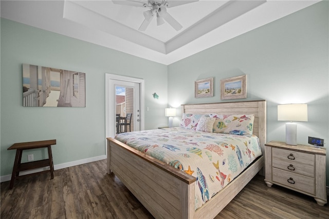 bedroom featuring dark wood-type flooring, ceiling fan, a raised ceiling, and access to exterior