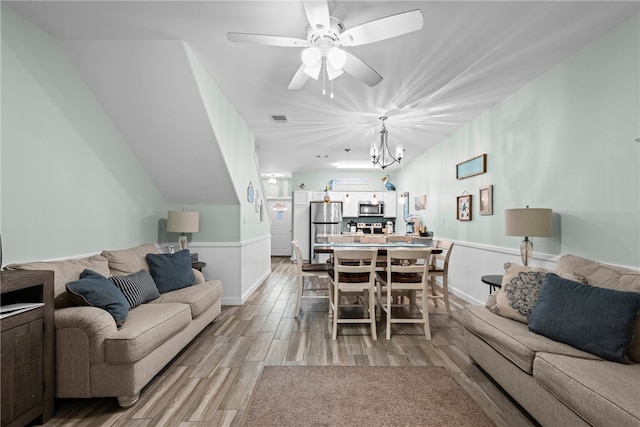 living room with ceiling fan with notable chandelier and light hardwood / wood-style floors