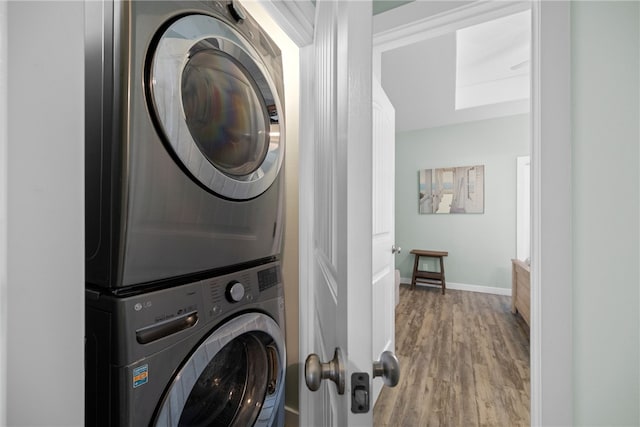 laundry room featuring hardwood / wood-style floors and stacked washer and clothes dryer