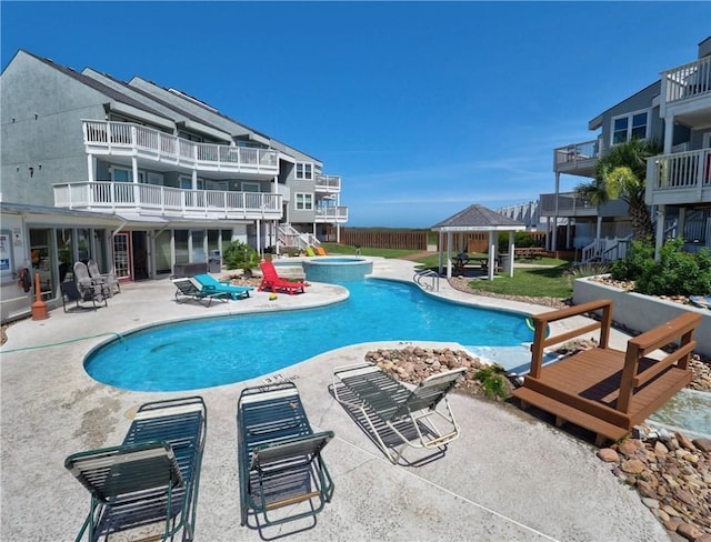 view of swimming pool featuring a gazebo, fence, a pool with connected hot tub, and a patio area