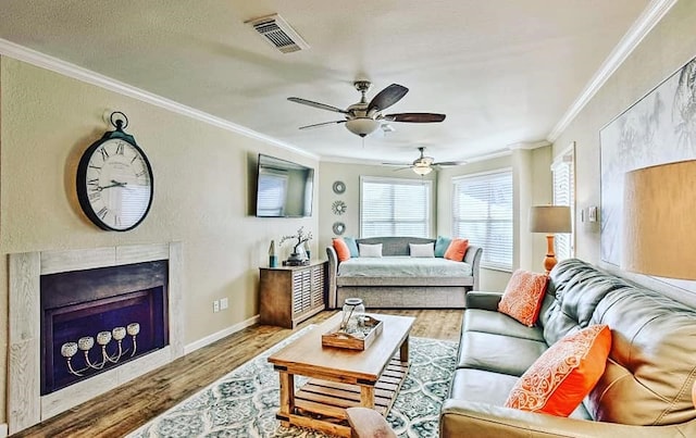 living room featuring crown molding, wood finished floors, visible vents, and a premium fireplace