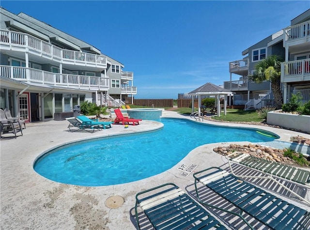 community pool featuring a gazebo, a patio area, a hot tub, and fence