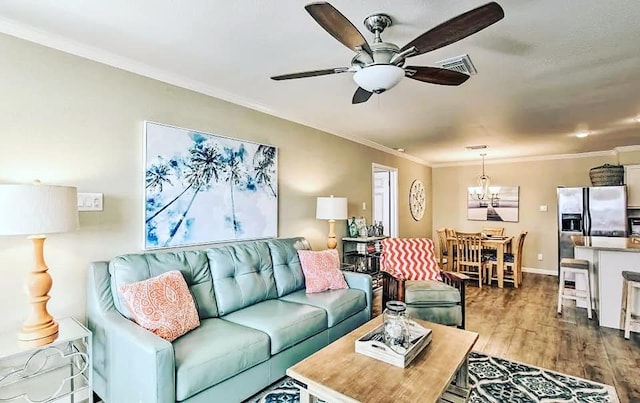 living area featuring visible vents, crown molding, baseboards, ceiling fan with notable chandelier, and dark wood-style floors