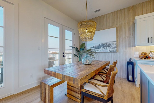 dining space featuring french doors, light hardwood / wood-style floors, and a notable chandelier