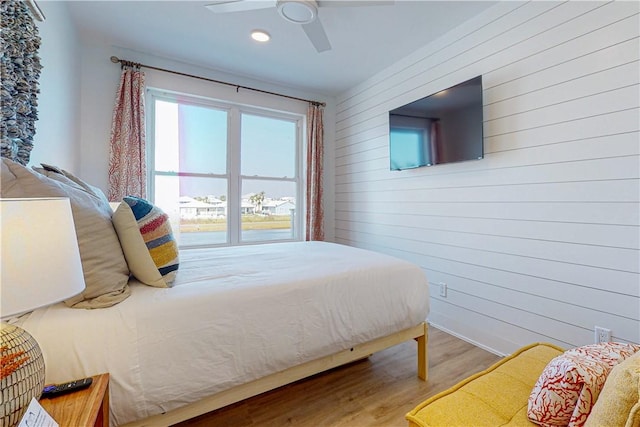 bedroom with wood-type flooring, ceiling fan, and wooden walls