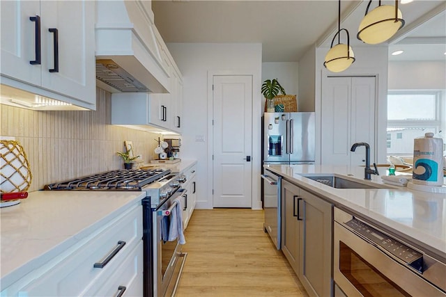 kitchen featuring hanging light fixtures, white cabinetry, appliances with stainless steel finishes, and custom range hood