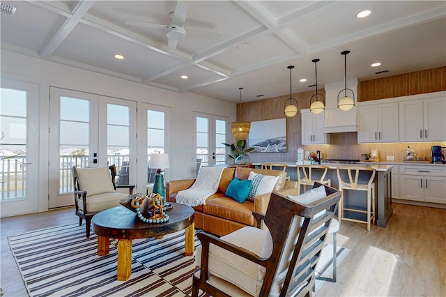 living room with french doors, coffered ceiling, beam ceiling, and light wood-type flooring