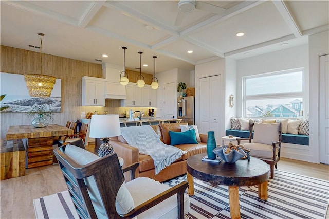 living room featuring coffered ceiling, beamed ceiling, and light wood-type flooring