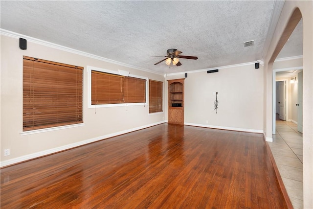 empty room featuring ceiling fan, wood-type flooring, a textured ceiling, and ornamental molding