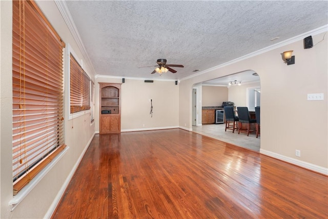 unfurnished living room featuring hardwood / wood-style floors, ceiling fan with notable chandelier, ornamental molding, and beverage cooler